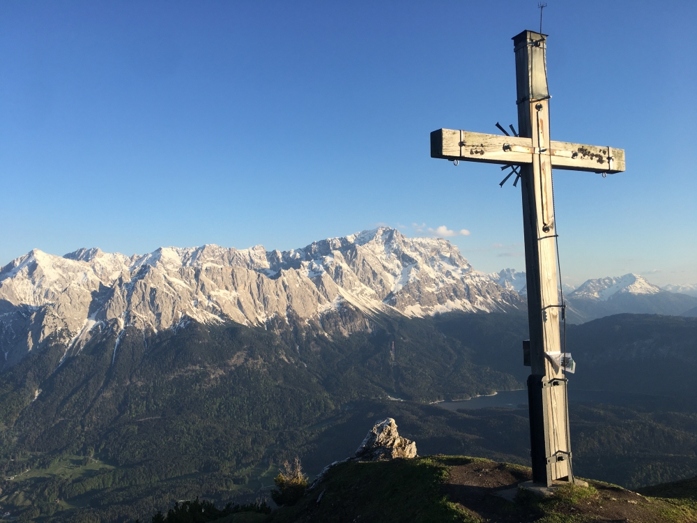 Hoher Ziegspitz: Gipfelkreuz Hoher Ziegspitz mit dem Juiläumsgrat zwischen Alpspitze (links) und Zugspitze (rechts) und dem Großer Waxenstein über dem Eibsee davor.